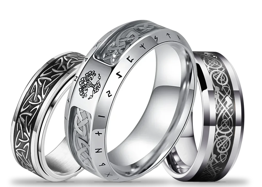 Three stainless steel rings standing side by side: a knotwork spinner ring, a rune band with the tree of life and a Celtic dragon inlay band